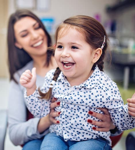 Young girl smiling during dental visit with dentist in modern clinic setting.