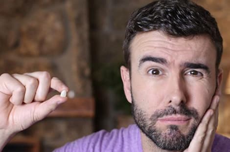 Man in purple shirt showing clenched fist, appearing frustrated about dental issue.