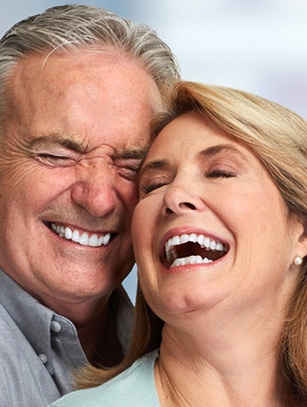 Smiling middle-aged couple enjoying outdoor moment, showcasing healthy, bright teeth.